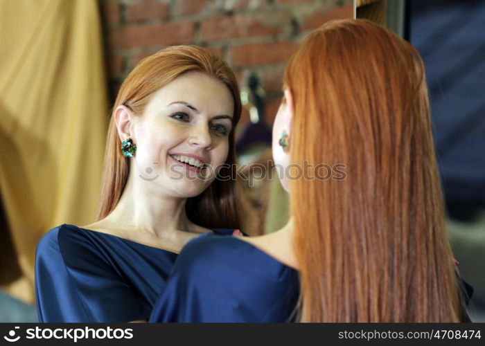 beautiful red-haired woman posing in front of a mirror