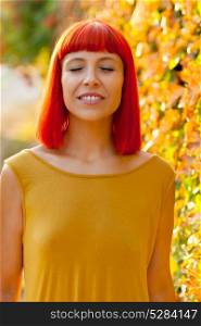 Beautiful red haired woman with closed eyes in a park lit with a golden light