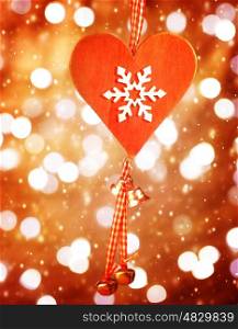Beautiful red heart shaped Christmas decoration with snowflake ornament hanging on blur shiny background, stylish christmastime bauble