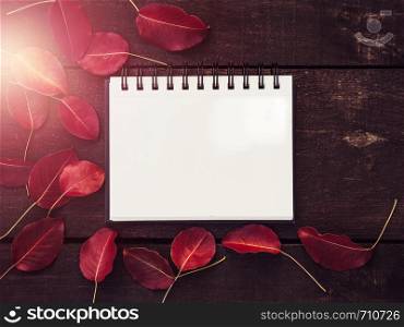Beautiful, red leaves, notebook and brown wooden planks and a place for your inscription. Top view, close-up. Congratulations to loved ones, family, friends and colleagues. Beautiful, red leaves, notebook and wooden planks