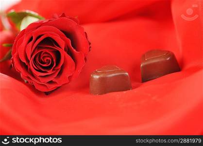 beautiful red rose and chocolate isolated on red close up