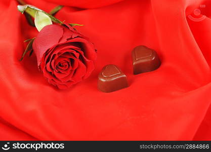 beautiful red rose and chocolate isolated on red close up