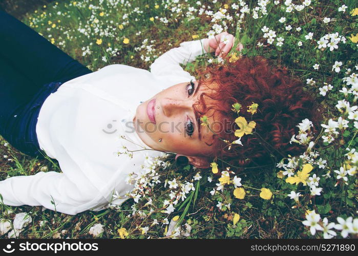 Beautiful redhead woman in a field of flowers