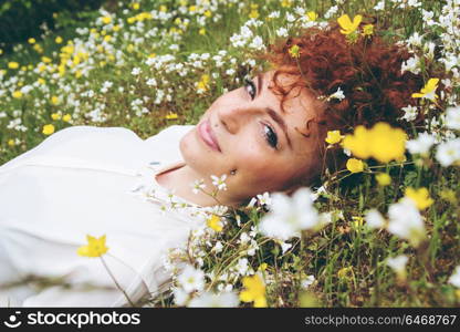 Beautiful redhead woman in a field of flowers