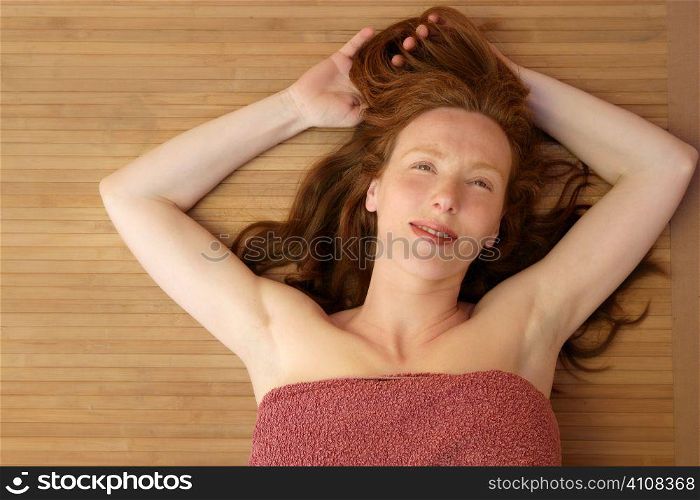 Beautiful redhead woman liying on bamboo in a golden spa center