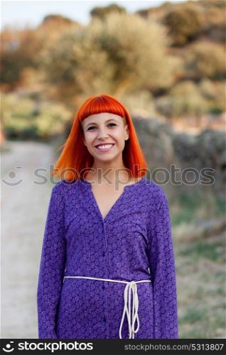 Beautiful redhead woman with a purple dress relaxed outside