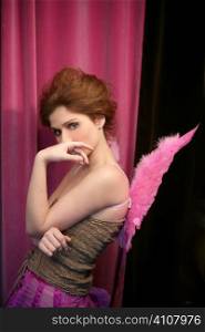 Beautiful redhead woman with pink feather wings on romantic soft light