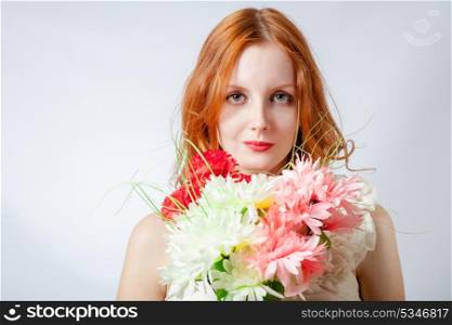 Beautiful redhead women looking at camera with flowers studio head and shoulders shot