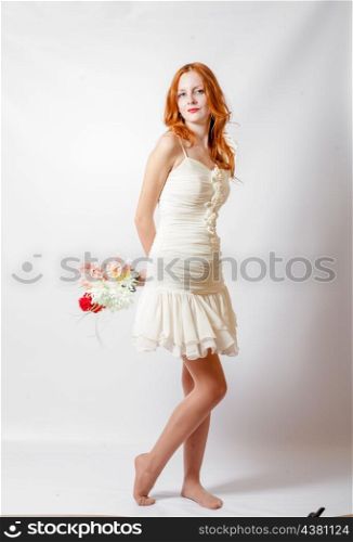 Beautiful redheaded girl with flowers studio full body shot