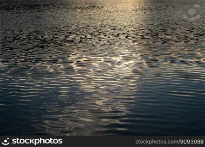  Beautiful Reflected the sun rays hitting the water surface river is waves the sea surface before sunset natural background.