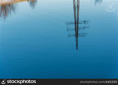 Beautiful reflection of the power line in the blue mirror smooth surface of the river.