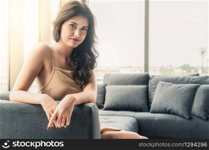 Beautiful relaxed business woman sitting on sofa couch in highrise office building tower.