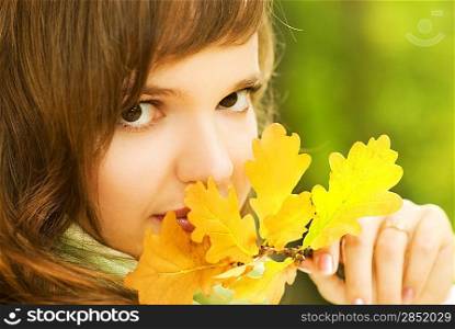 Beautiful romantic brunette with golden autumn leaf close-up portrait