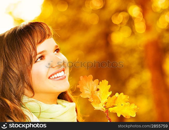 Beautiful romantic brunette with golden autumn leaf close-up portrait