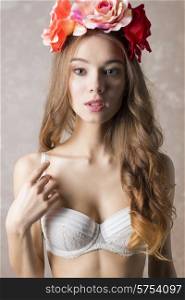 Beautiful, romantic, retro woman in white bra and flowers on head, she has got curly, long hair and natural make up.