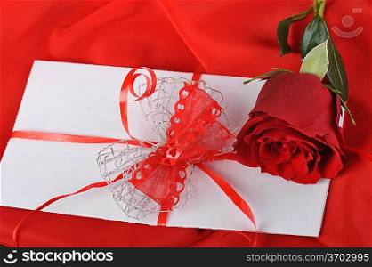 beautiful rose and letter with ribbon on red close up