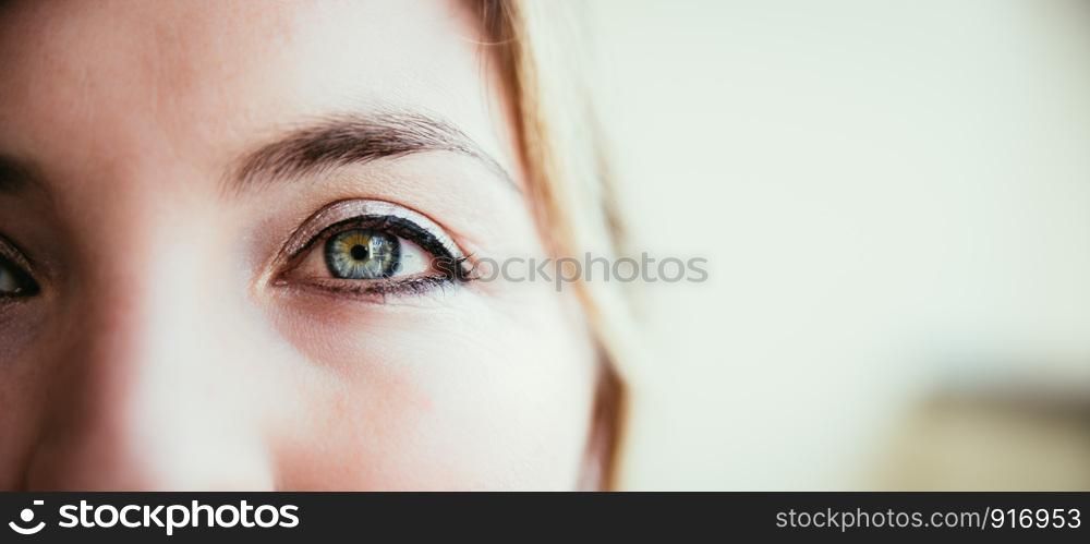Beautiful rouged blue eye of a young girl, closeup and text space