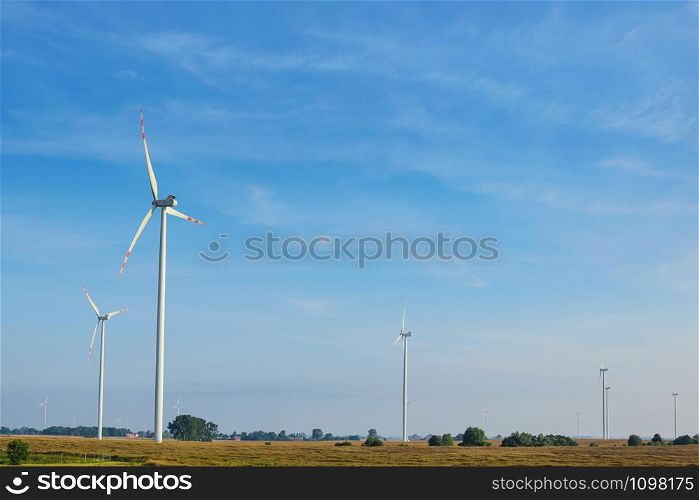Beautiful rural landscape with ecological wind farms on the blue sky background