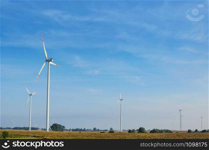 Beautiful rural landscape with ecological wind farms on the blue sky background