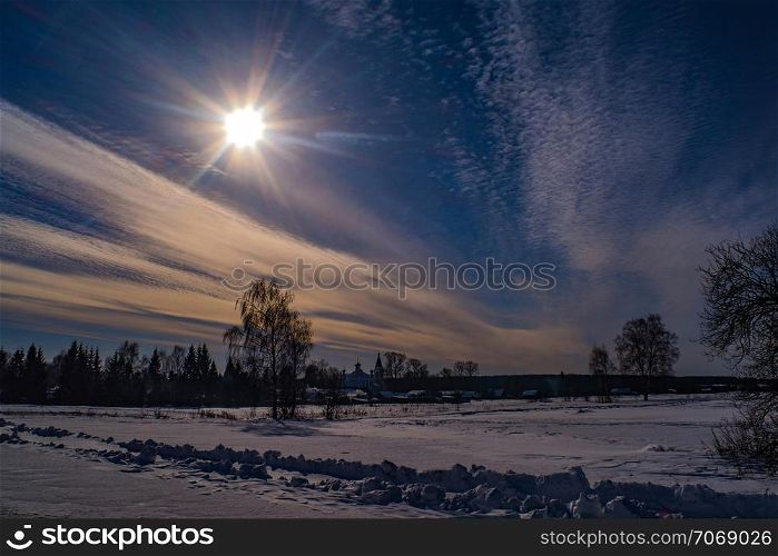 Beautiful rural winter landscape with bright sunshine against the blue sky with beautiful clouds.