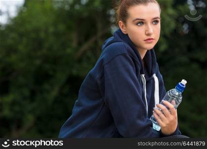 Beautiful sad depressed girl teenager female young woman drinking bottle of water outside