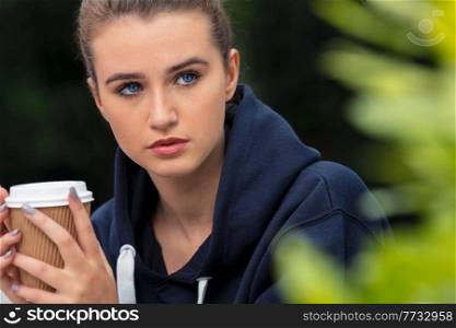 Beautiful sad depressed girl teenager female young woman drinking take out coffee outside, mental health concept