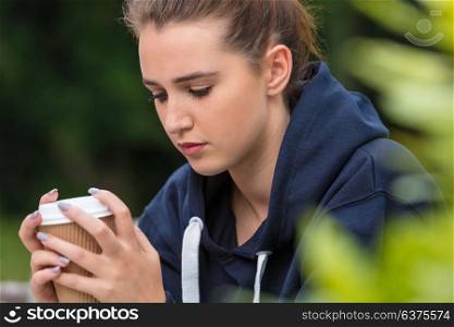 Beautiful sad depressed girl teenager female young woman drinking takeaway coffee outside