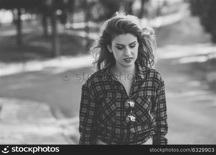 Beautiful sad young woman in the park. Girl with long blonde curly hair. Black and white photograph