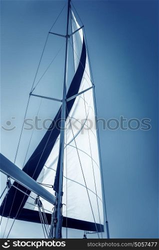 Beautiful sailboat, big white sail fluttering in the wind on clear blue sky background, luxury sea cruise, summer vacation concept