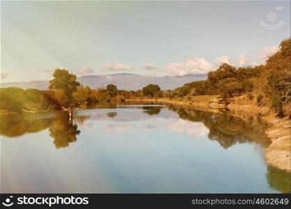Beautiful scenery of the banks of a river with oak trees reflected in water