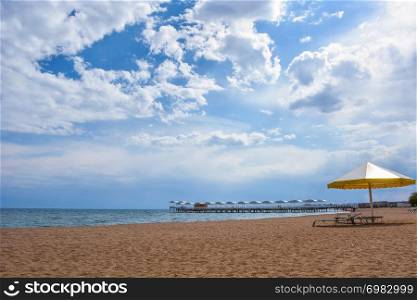 Beautiful scenic view - distant open wood amid the calm water of Issyk-Kul Lake against the background of Tien Shan mountain range and cloudy blue sky, Kyrgyzstan, Central Asia