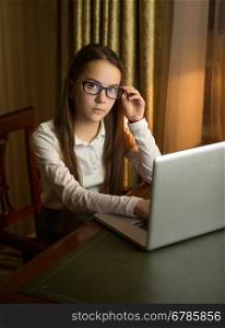 Beautiful schoolgirl wearing eyeglasses posing with laptop