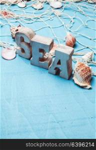Beautiful sea composition wooden letters and fishing net on blue background. Sea interior decorations