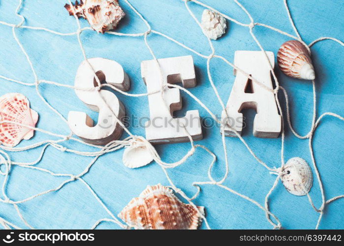 Beautiful sea composition wooden letters and fishing net on blue background. Sea interior decorations