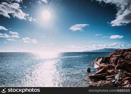 Beautiful sea landscape. Ocean water calmly waving next to rock coastline during summer warm weather.. Sea next to rock coastline