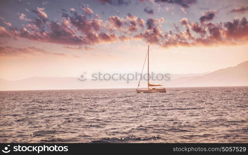 Beautiful sea landscape, sailboat sailing in the distance in mild pink sunset light, romantic vacation in the sea, beauty of summer nature