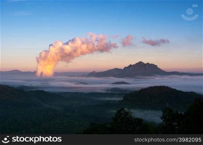 Beautiful sea of fog in the mountains, high voltage pole and steam from the coal power plant in the morning sunrise . Mae moh, Lampang, Thailand. Energy and environment concept .. Sea of fog and coal power plant.