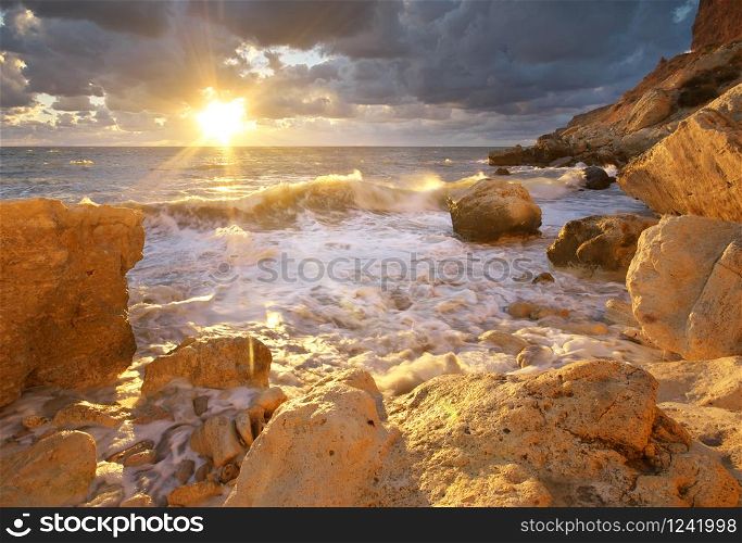 Beautiful seascape. Sea waves during storm on sunset splash on stones. Composition of nature.
