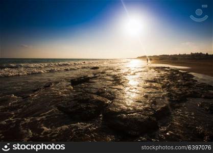 Beautiful seascape with silhouette of walkers on a sandy beach in summertime. The beautiful seascape