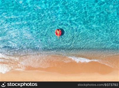 Beautiful seascape with woman with red swim ring in blue sea at sunset in summer. Aewrial view. Tropical scenery with girl, clear water, waves, sandy beach. Top view. Vacation. Sardinia island, Italy	