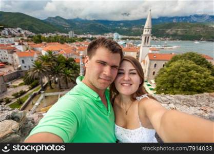 Beautiful selfie of young couple in love posing against old city of Budva, Montenegro