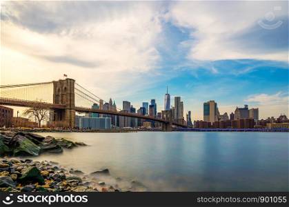 Beautiful sence of Brooklyn bridge and lower manhattan of New York city in dusk evening. Downtown of lower Manhattan of New York city and Smooth Hudson river with sunset light.