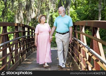 Beautiful senior coule stays fit by walking together in the park.