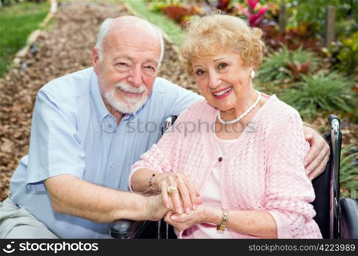 Beautiful senior couple outdoors. The wife is in a wheelchair.