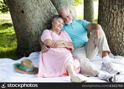 Beautiful senior couple relaxes in the shade at the park.
