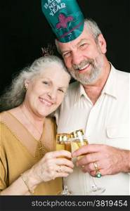 Beautiful senior couple toasting in the New Year with champagne. Black background.
