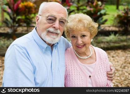 Beautiful senior couple together in their garden. Focus on her.