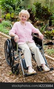 Beautiful senior lady smiling outdoors in her wheelchair. Full body view