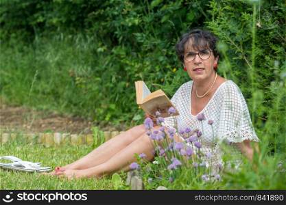 beautiful senior woman reading a book in the garden