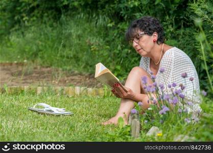 beautiful senior woman reading a book in the garden